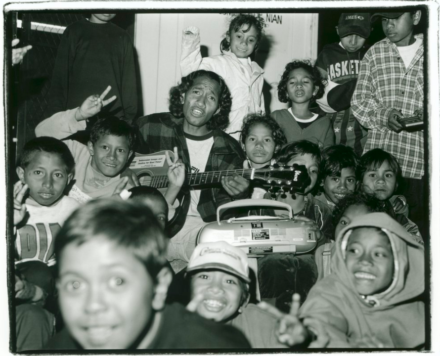 An East Timorese refugee, singing and playing the guitar, surrounded by East Timorese children at the Puckapunyal Safe Haven