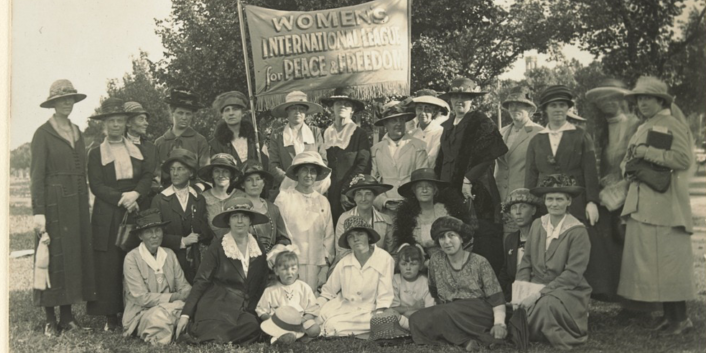 A collection of women gathered under a banner.