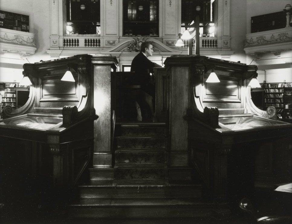 Photograph of the Dais in the Domed reading room, showing the library attendant sitting within it in profile.