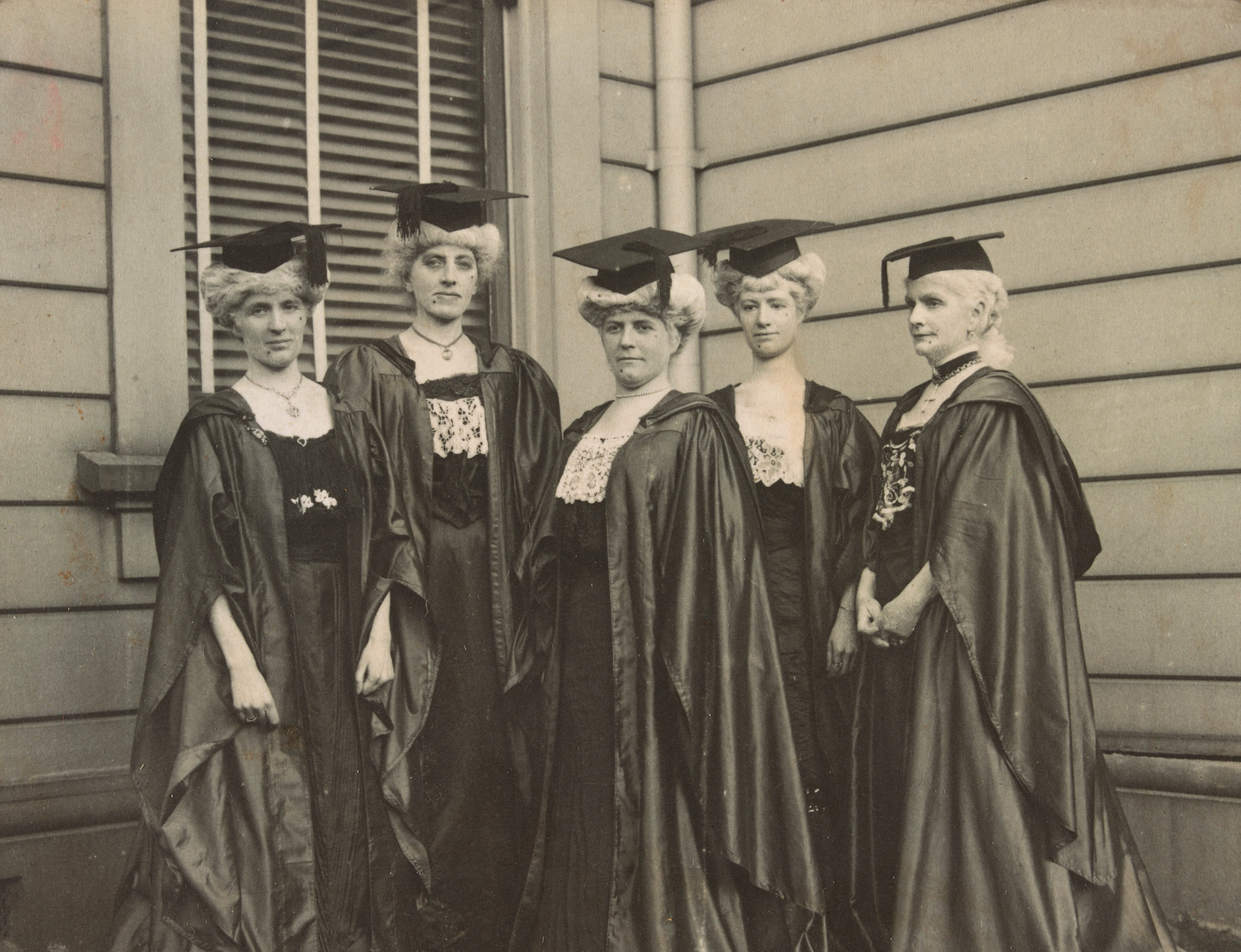 Five women in academic gowns, wigs and beauty spots