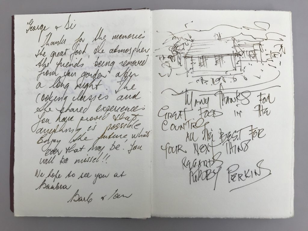 A small book laying open, revealing handwritten text from two different people, across its pages. 
