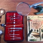 Book, tools and magnifying glass on table