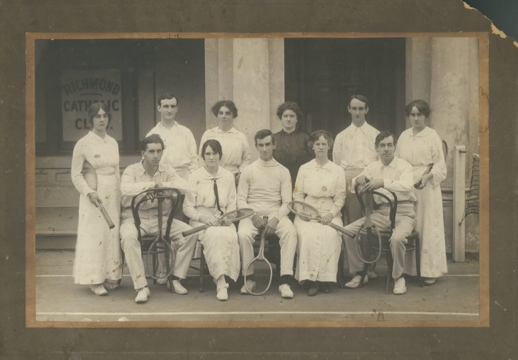 group portrait of men and women dressed in tennis attire of the early 1900's - long skirts for the women, long trousers for the men.