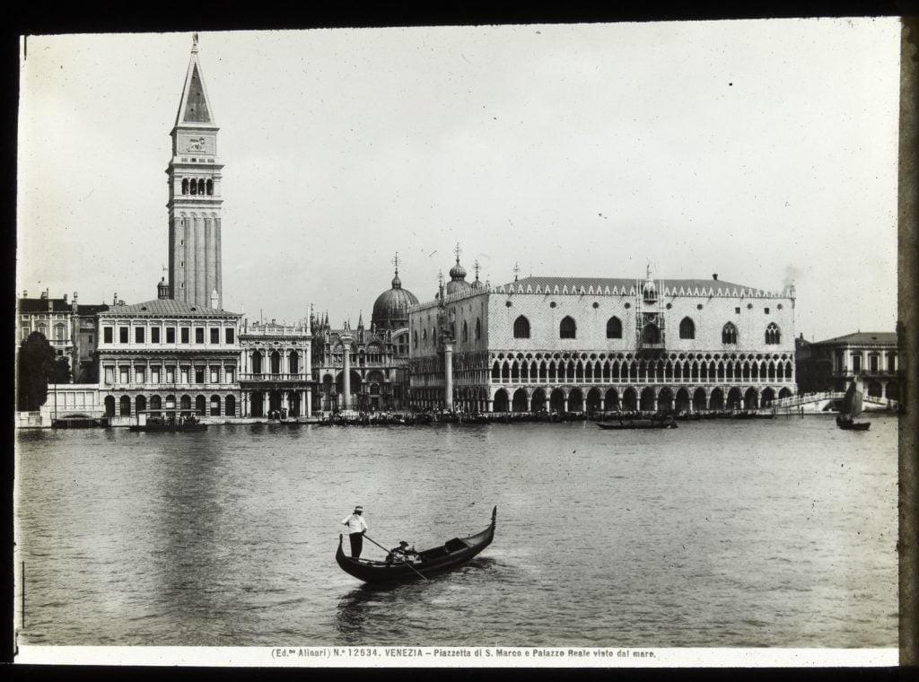 Venezia - Piazzetta di S. Marco e Palazzo Reale viste dal mare: Looking across water towards St. Marks Square -- View along a canal with couple seated in a gondola in foreground -