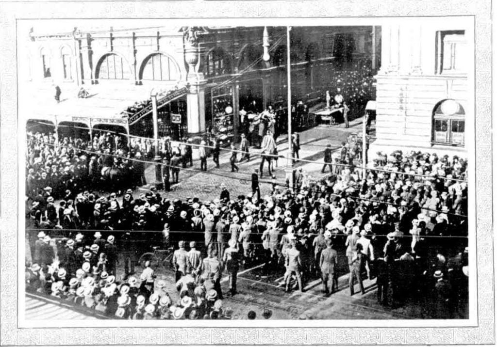 Detail from newspaper article showing large crowd gathered around the entrance of the T & G building. 
