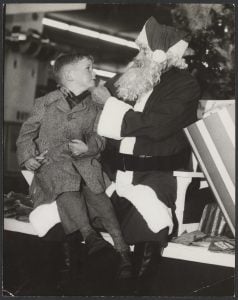 Black and white photo of a young boy sitting on Santa's knee