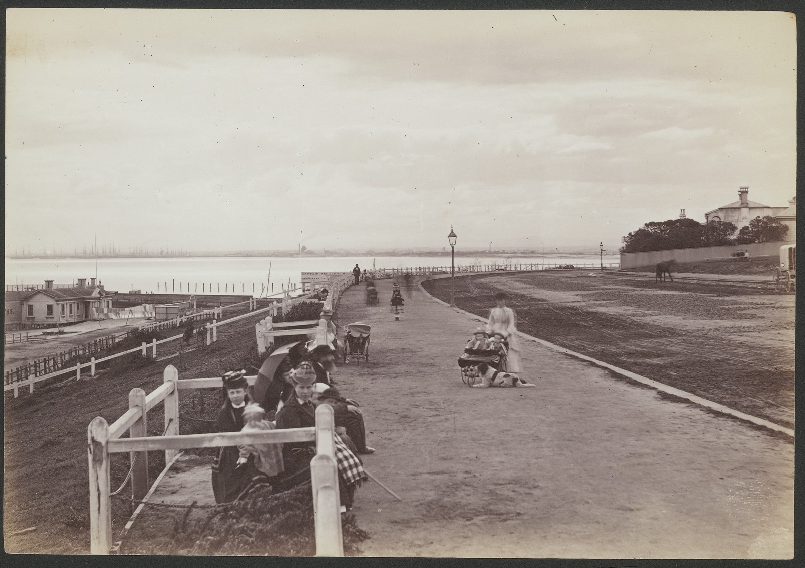 Black and white photo of the St Kilda esplanade with a sign advertising Captain Kenney's baths in the background