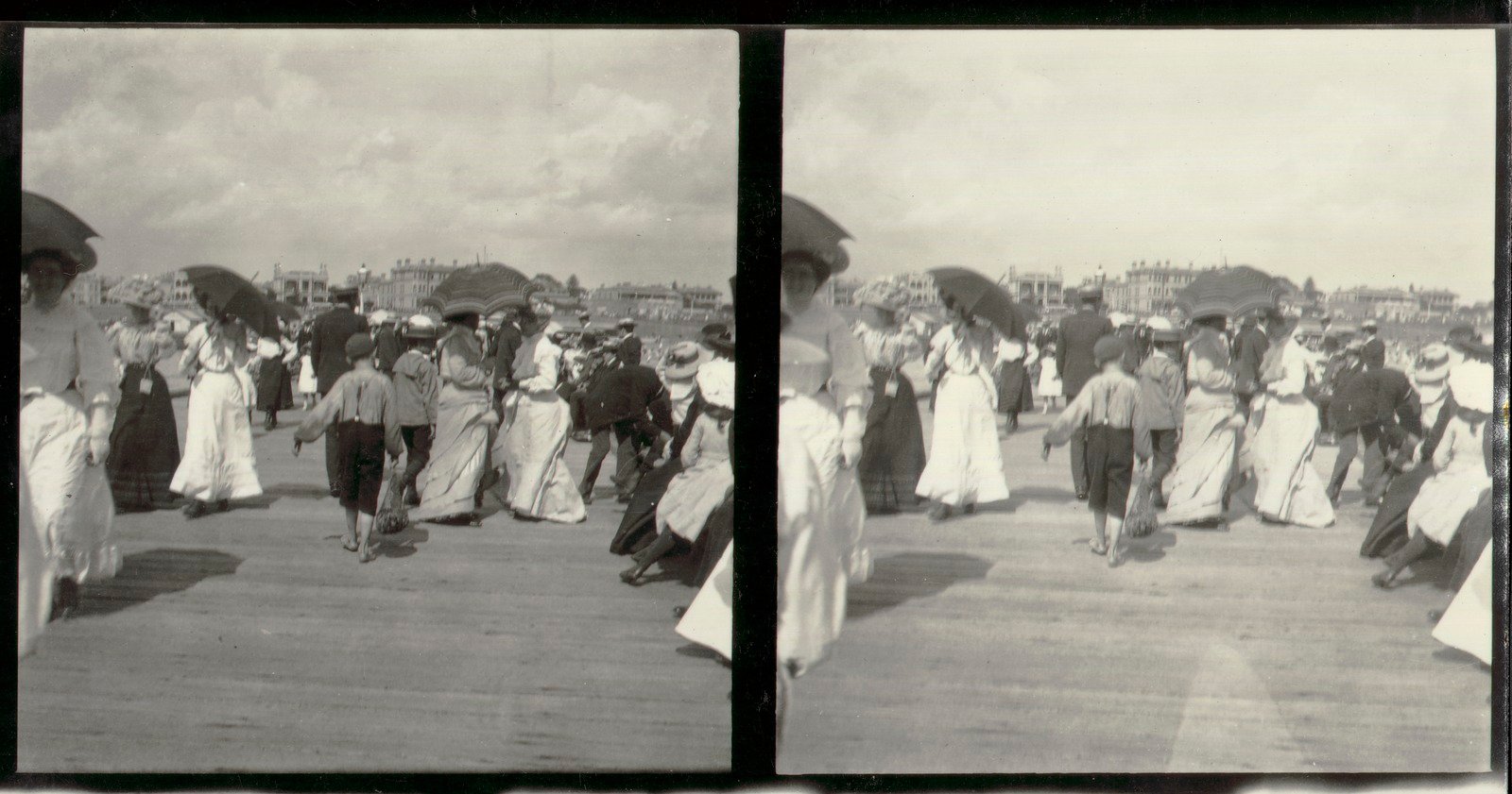 Black and white photo of crowds in 19th century dress wandering along the St Kilda foreshore