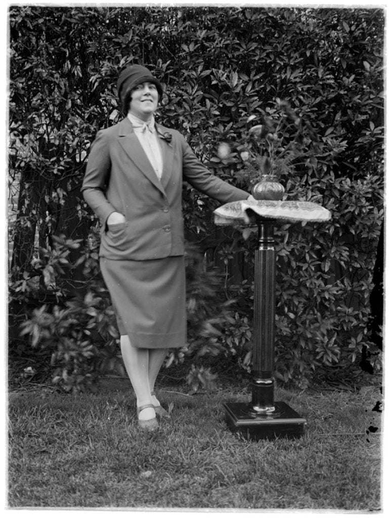 A woman dressed in a suit standing in a garden