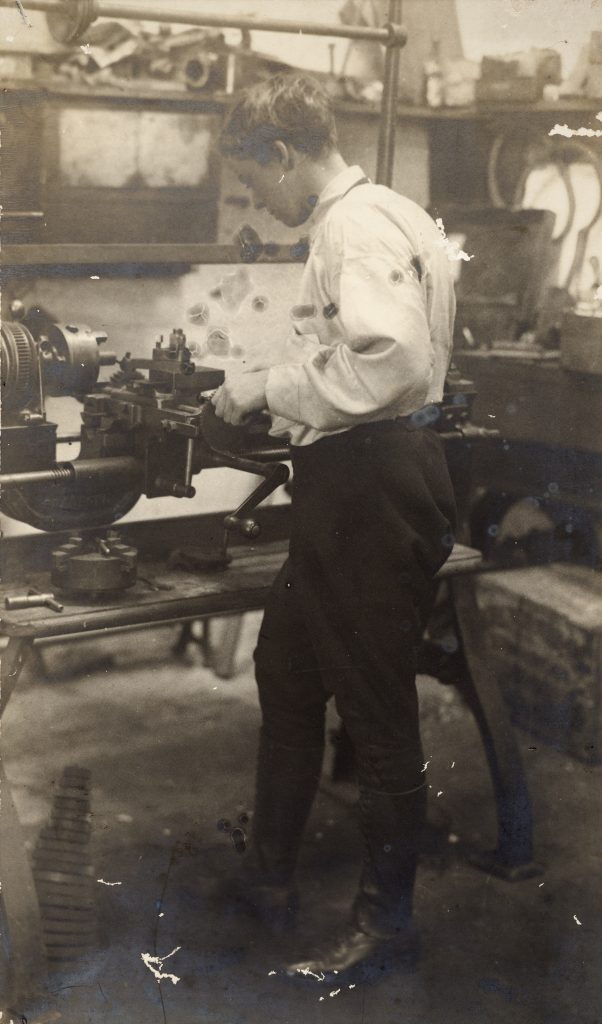 Black and white photo of Alice Anderson in her overalls working at a lathe in her garage