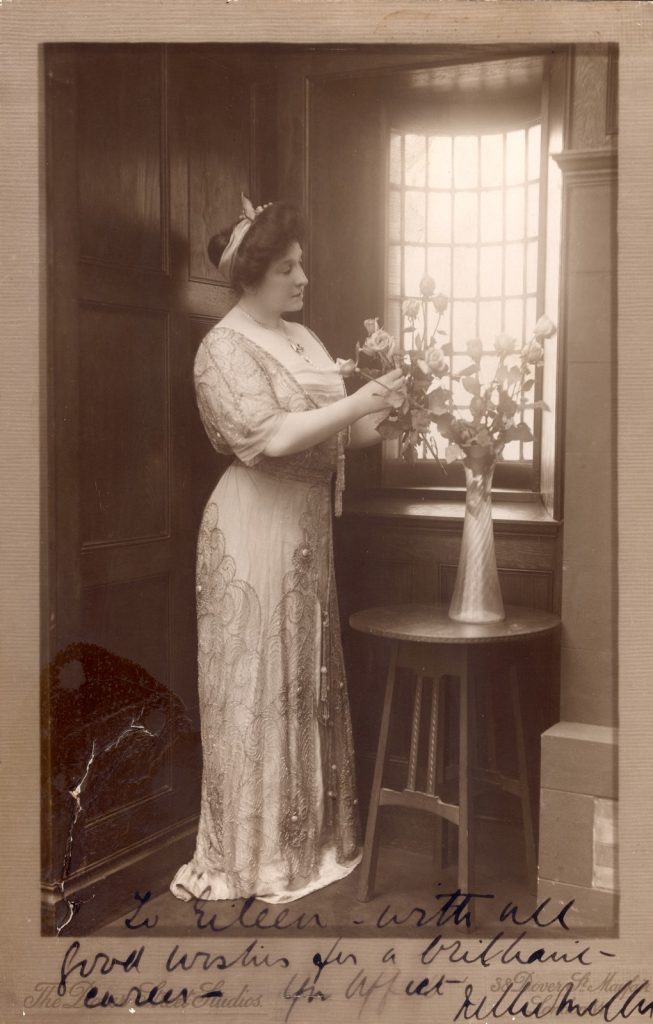 Black and white photo portrait of Nellie Melba next to a vase of roses.