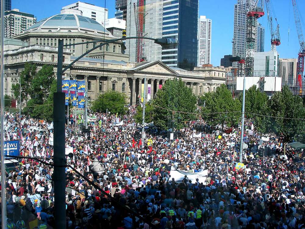 Colour photograph of protesters gathered outside the State Library in Swanston Street, Melbourne peace rally. Large crowd occupying entire city intersection.