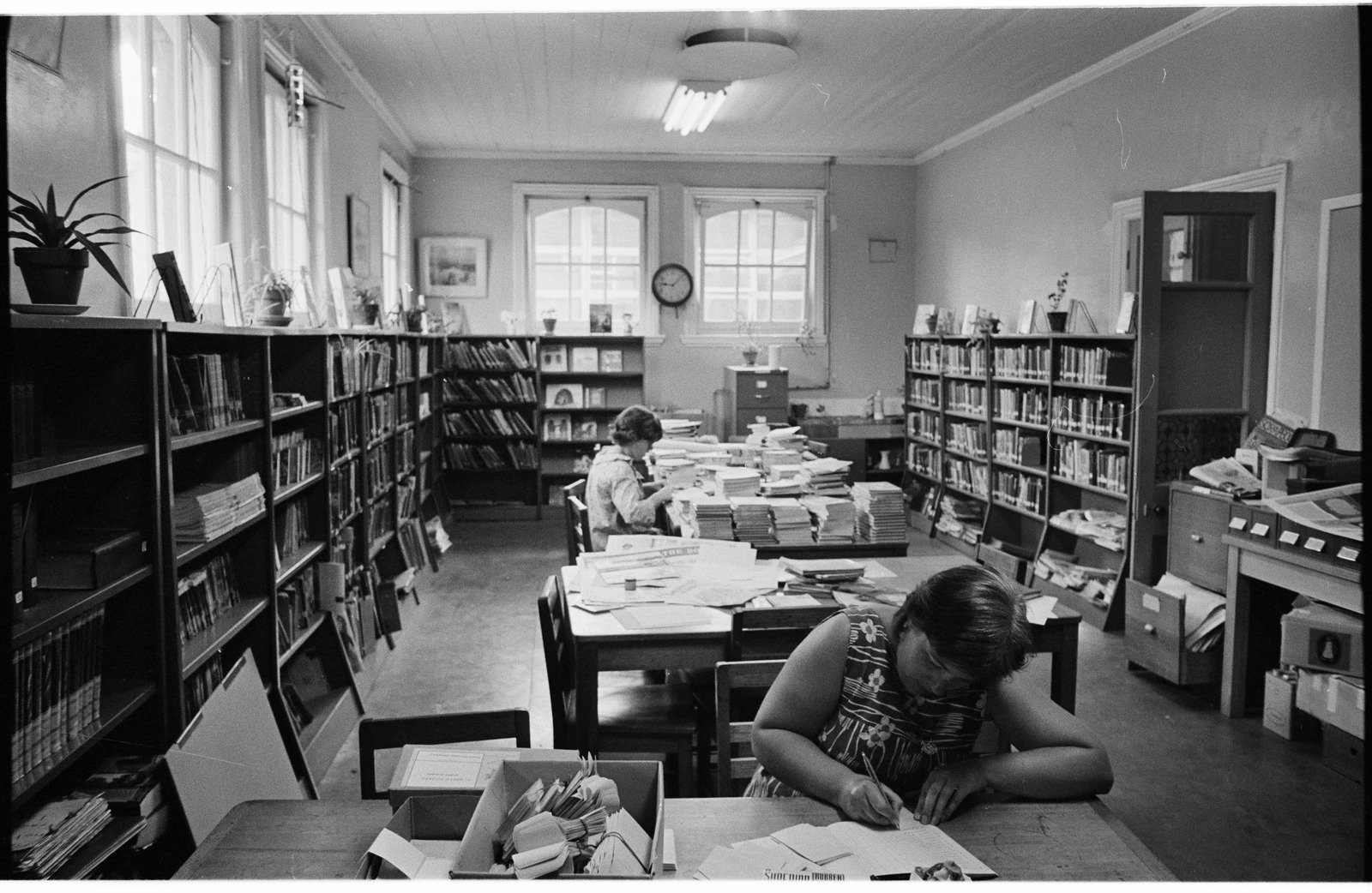 North Fitzroy school library with walls edged with bookshelves and 2 library staff working at desks