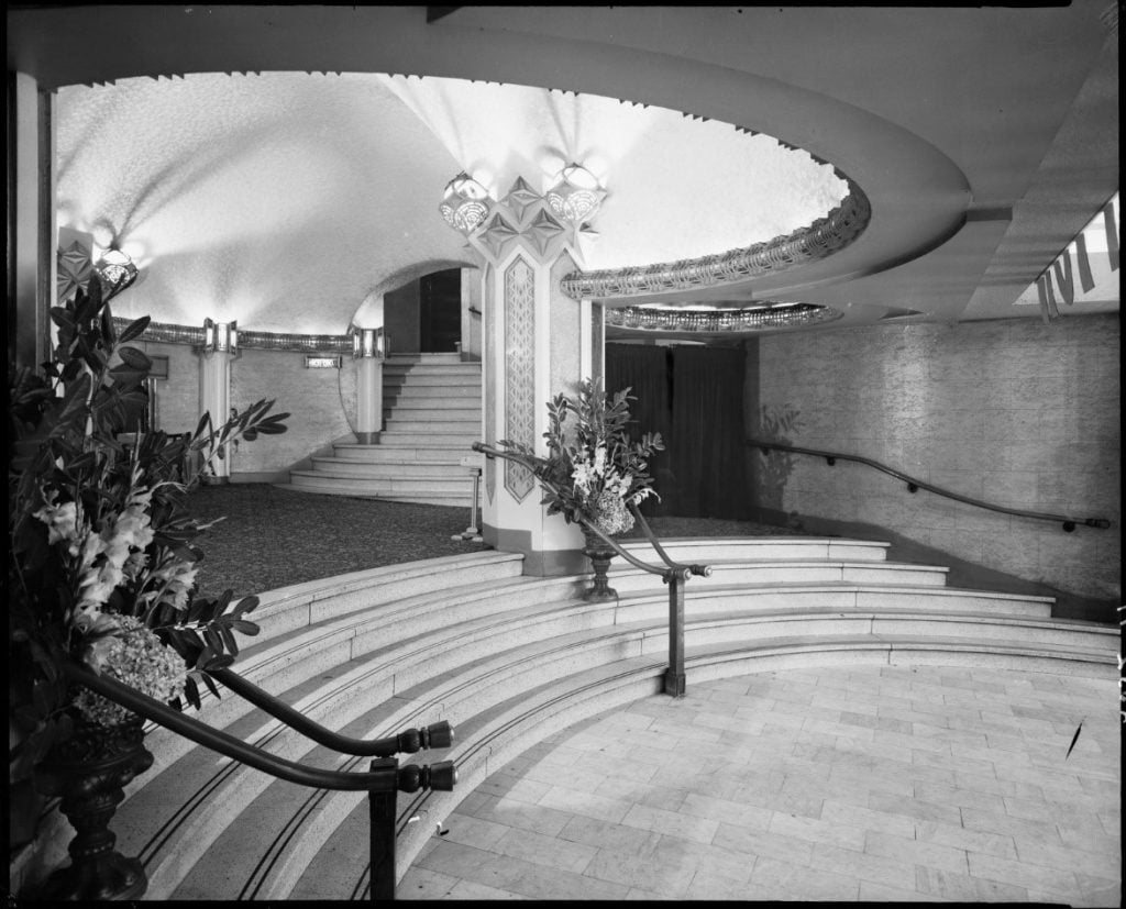 Interior of the Capitol Theatre with ornate stairs and bouquets of flowers in large vases