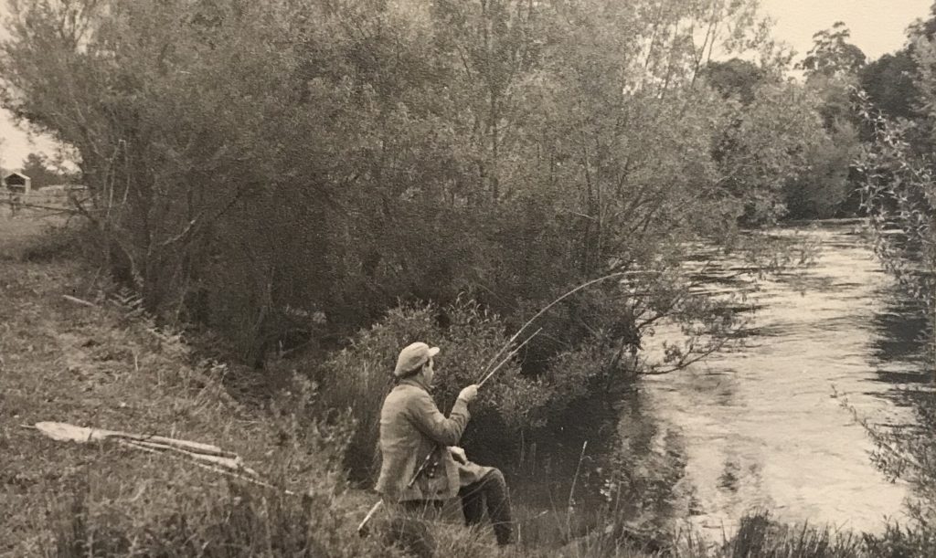 Dolia Ribush seated beside a river, fishing