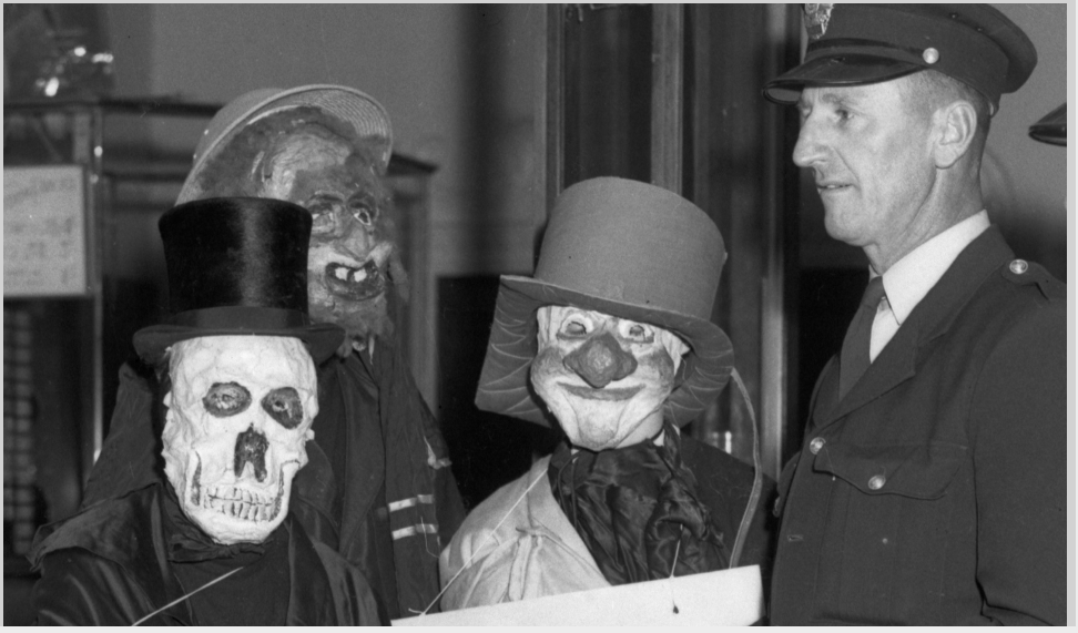 Detail of five figures in Halloween costumes standing at the entrance of a picture theatre