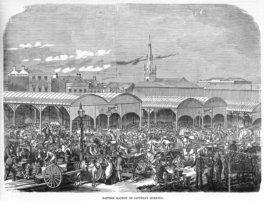 Wood engraving published in The illustrated Melbourne Post, depicting a lively and crowded scene of the Eastern Market. Roofed stalls are visible, and crowds of traders and their wares, as well as shoppers, and horse wagons loaded with produce.