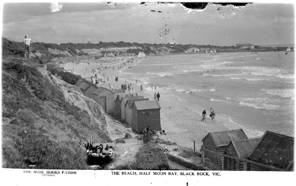 Stretch of coastline with small waves. Wooden bathing boxes in the foreground. 