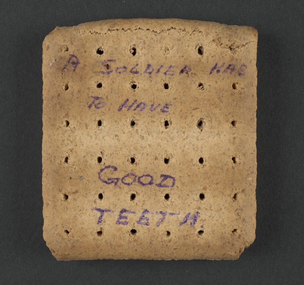 Reverse of an Army biscuit with the words "A soldier has to have good teeth" handwritten onto it