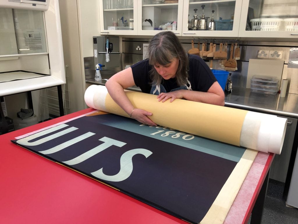 Rolling the flattened and repaired sheets onto an archival tube for rehousing in a custom archival box; H97.146/4. Image credit: Albertine Hamilton