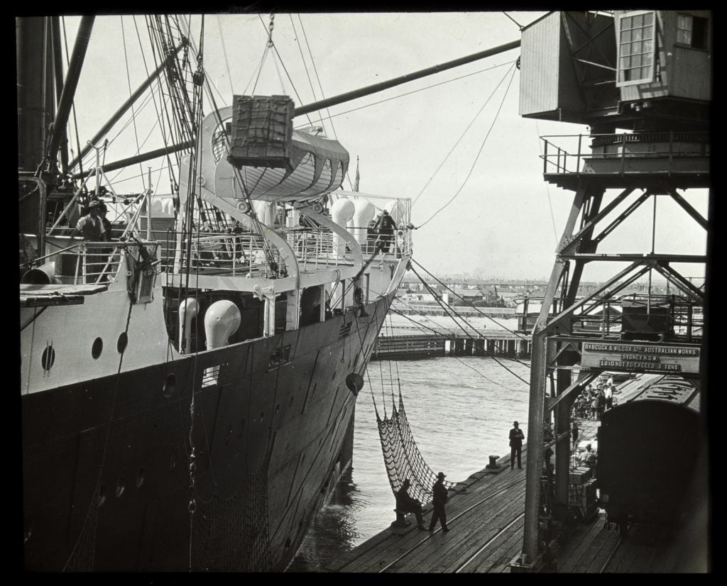 Image of cargo being loaded on a ship next to a pier.