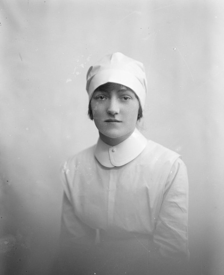 Photographic portrait of a nurse, in white uniform with starched collar and cap
