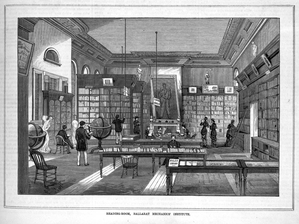 Black and white wood engraving of the interior of a reading room with tall bookcases lining the walls, men and women reading and conversing, 19th century world globes on timber stands, a large portrait painting of a man on an easel at the back, chairs and tables positioned around the room and a sign demarcating a ladies only area. 