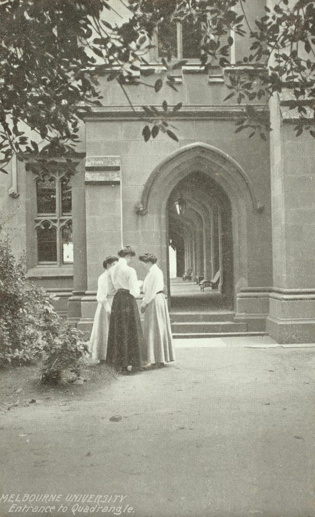 Sepia photo printed on a postcard of three women standing near entrance to the cloisters, on the north wing of the quadrangle at the University of Melbourne in around 1910