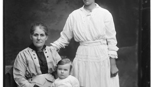 two women and a baby, the older woman seated holding the baby on her lap