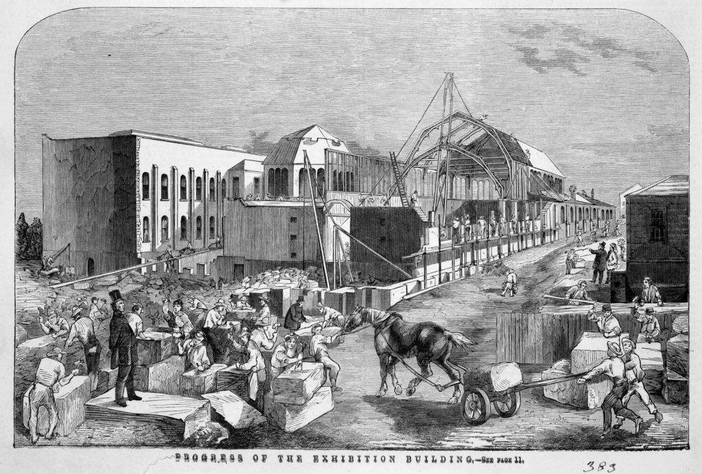 wood engraving showing construction of the great all, with horse pulling large stone block on a trolley, workmen chiselling large blocks of stone and a man wearing a top hat standing and overlooking the works.