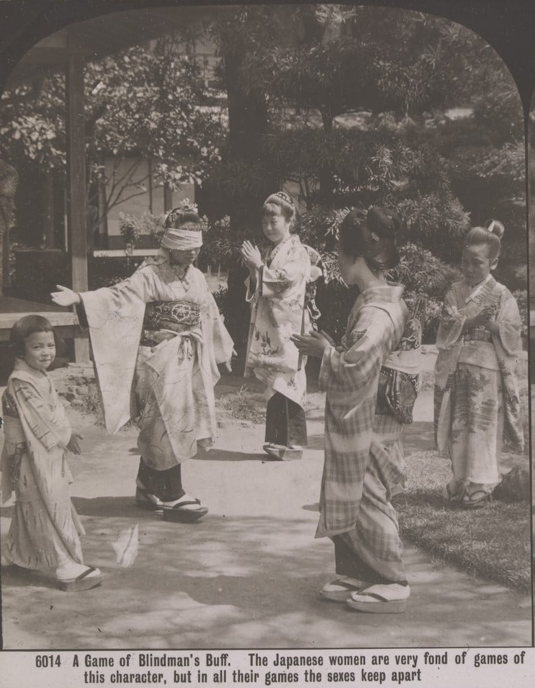 Four Japanese women and a little girl wearing kimonos play blindman's buff. One woman wears the blindfold, while the others watch. 