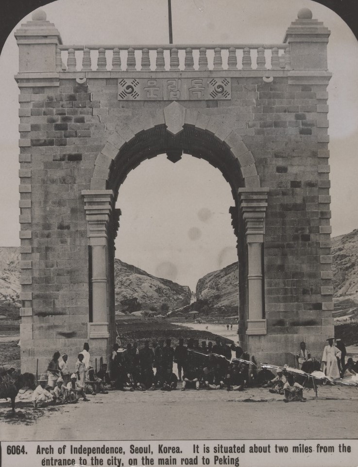 Japanese soldiers stand and sit at the Arch of Independence, Seoul, Korea, 1905. The road to Peking (Beijing) is in the background.