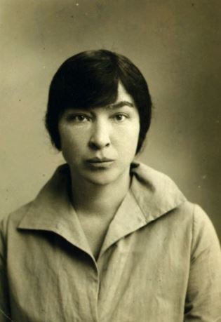 Sepia-toned head-and shoulders photograph which appears to be a passport or identity photo, of a young woman wearing a linen shirt with her hair tied back. 