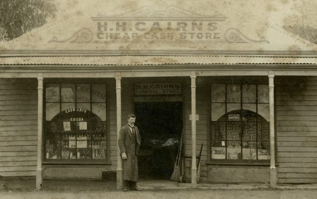 Man in suit standing outside a General Store.