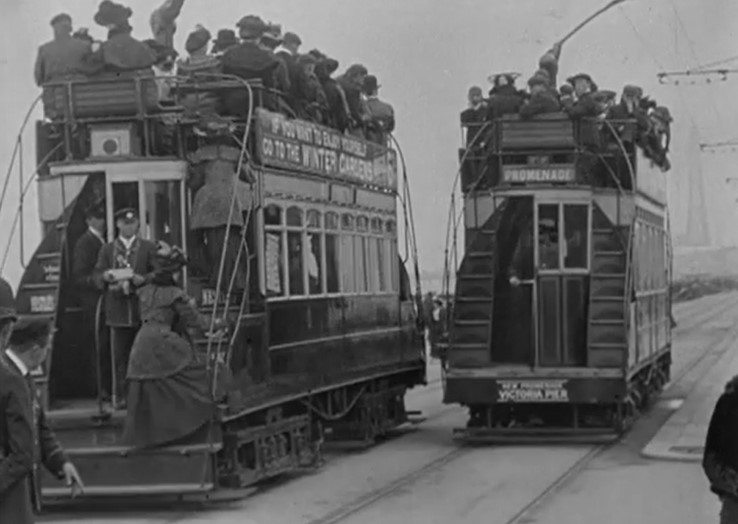 still frame of two trams passing. Black and white image.