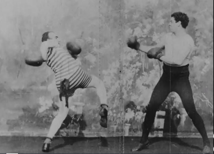still frame of two men boxing. Black and white image.