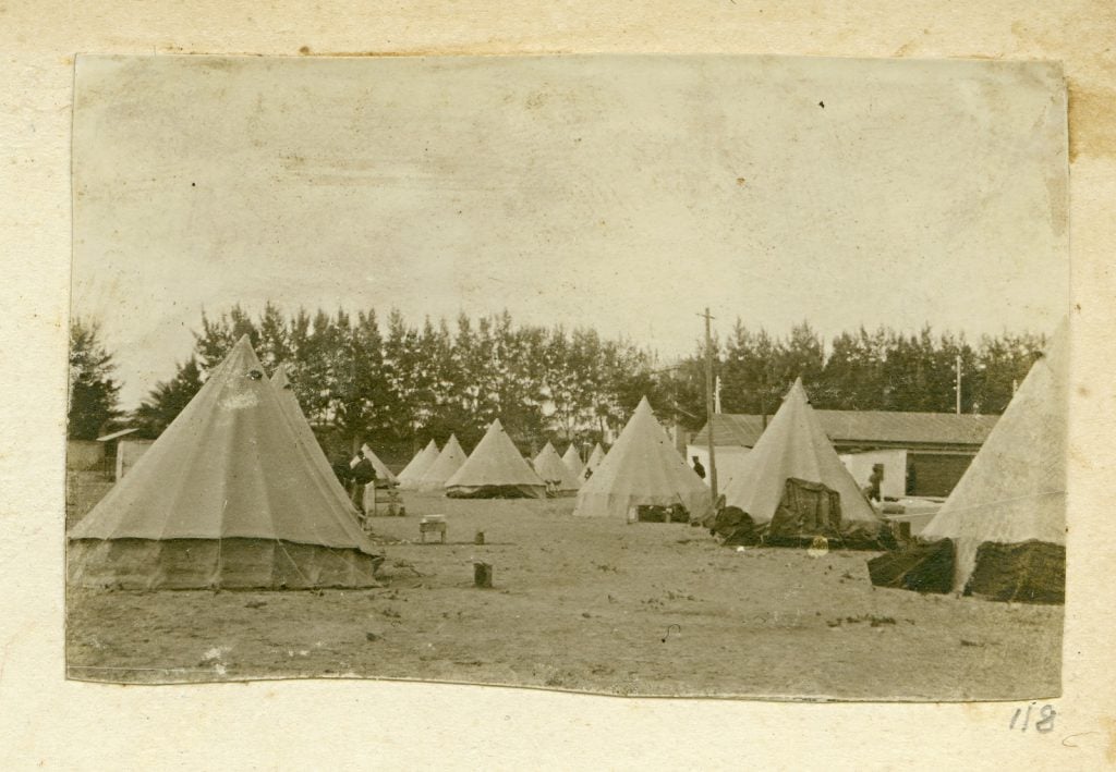 Open tree-lined ground with tents.