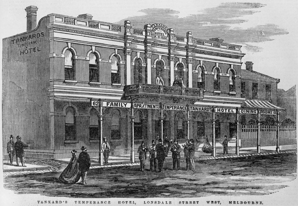 Engraving depicts a large double storey hotel, with some figures on the upstairs balcony and out the front on the street.