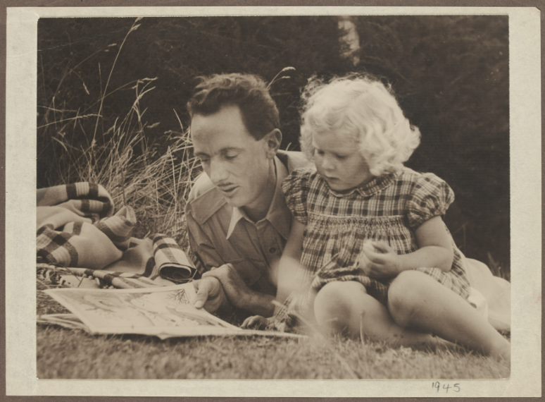 Black and white photograph show a man lying on the grass with a small girl, reading a book.