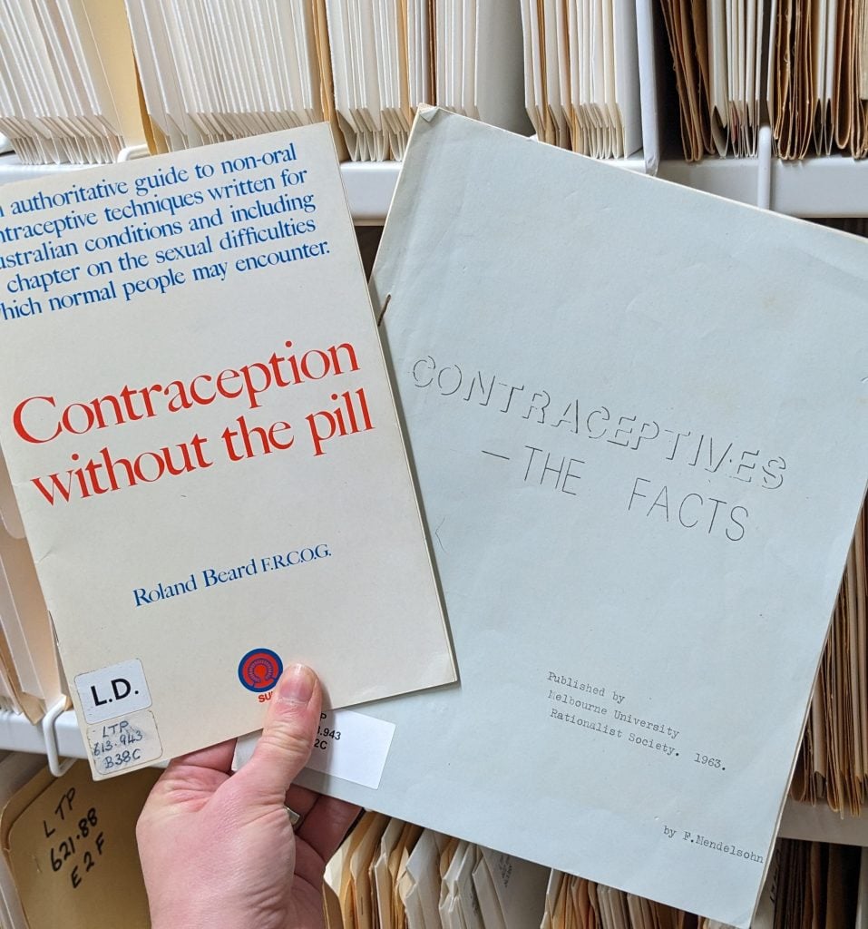 A photograph of a hand holding two printed pamphlets regarding Contraception.