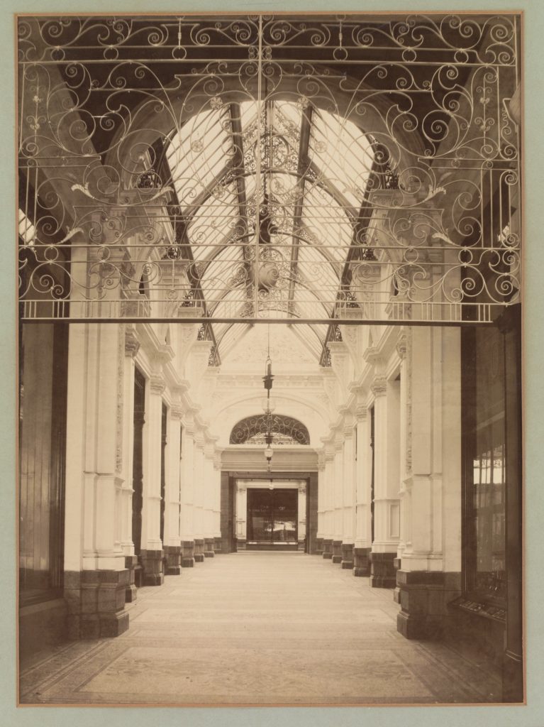 Photo of one of the grand arched walkways of the Block Arcade at the time of opening. Decorative ironwork and the glass ceiling are prominent.