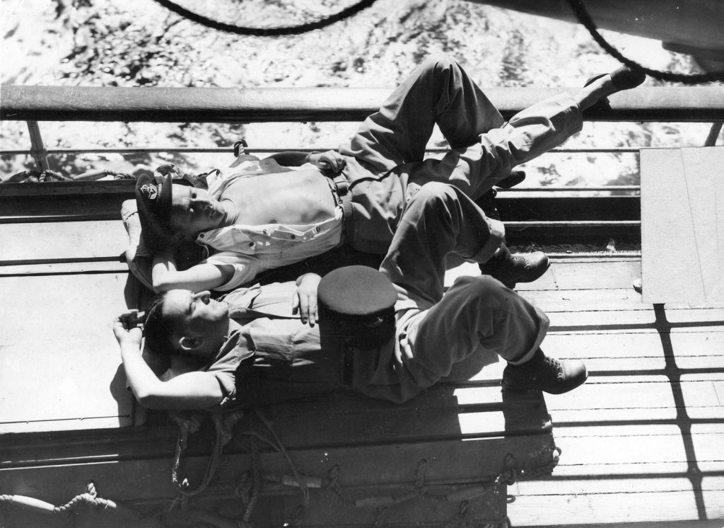 Two R.A.A.F. men sunbathe on troopship northward bound in South West Pacific area