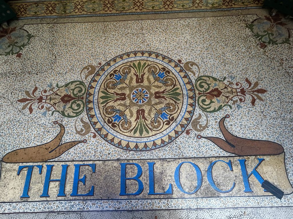 A photo of section of the elaborate mosaic floor of the Block Arcade, including stylisied rendering of the words "The Block".