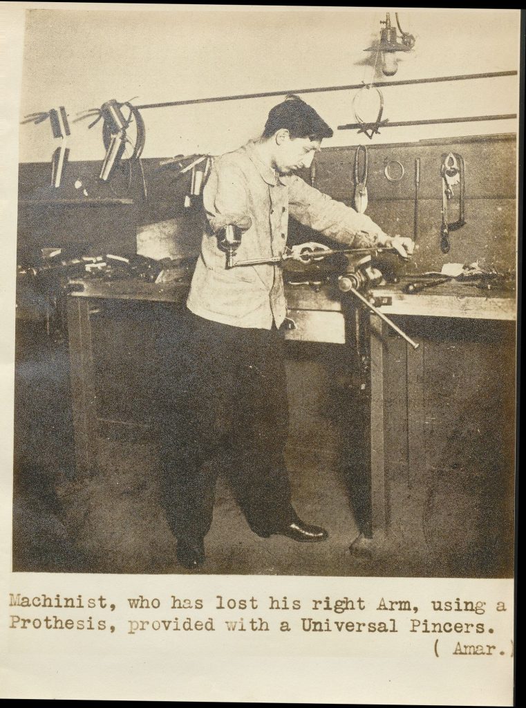 Black and white photo of machinist in workshop using prosthetic right arm.