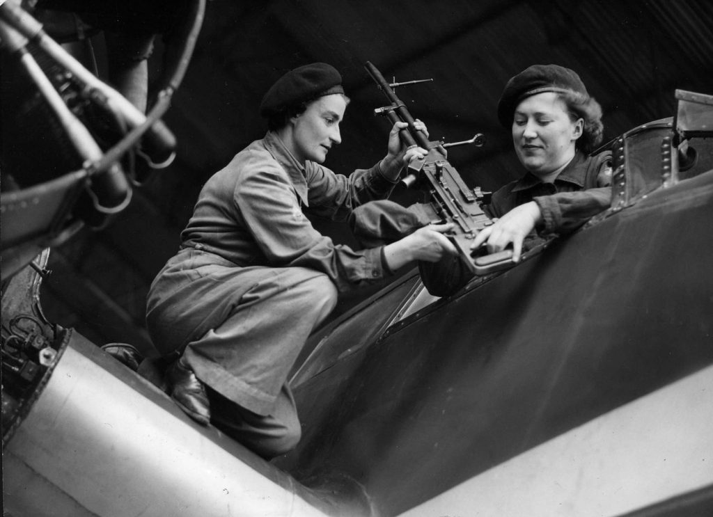 Showstwo women armorers fitting a machine gun into an aircraft.