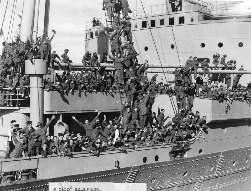 Shows dozens of troops aboard a naval ship