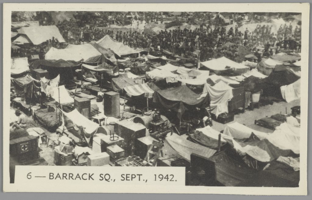 Aerial view of Changi barracks, showing crowds of POWs, makeshift tents and shelters.