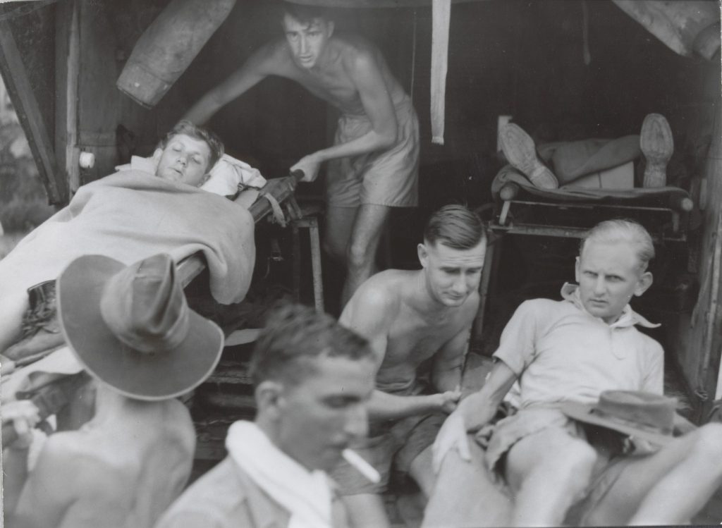 Shows stretcher cases being carefully loaded into an ambulance.
Shows wounded prisoners-of-war being carefully loaded into an ambulance.