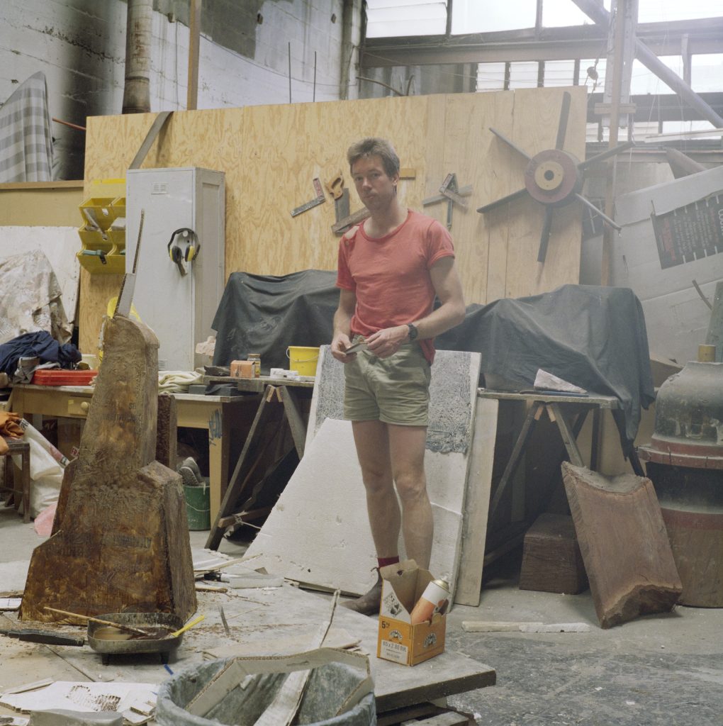 Photo of Mark Stoner standing in his workshop looking at the camera, surrounded by tools.