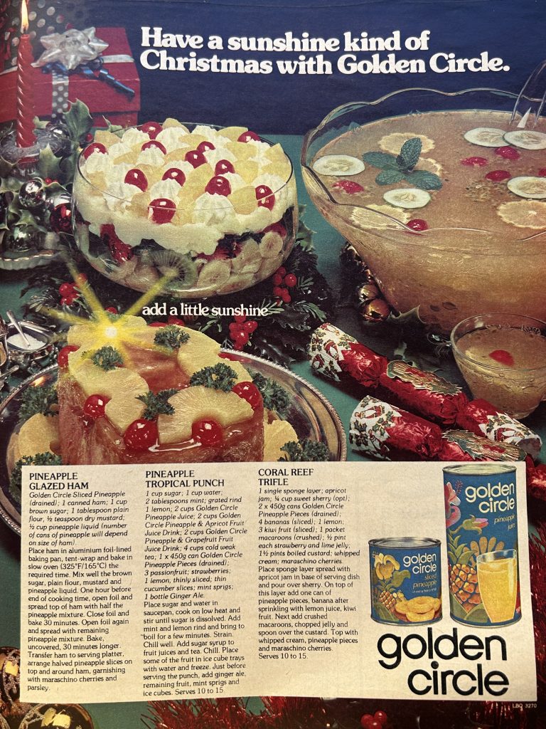 Colour photo of punch bowl, ham and trifle featuring pineapple on a decorated table